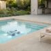 A cordless pool cleaner in a clean and uncluttered backyard pool setup